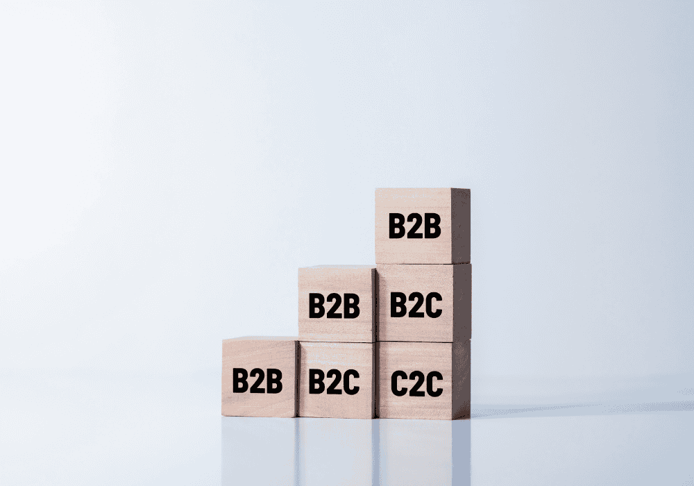 Wooden blocks with the terms "B2B", "B2C", and "C2C" stacked in a pyramid shape, representing different e-commerce business models.