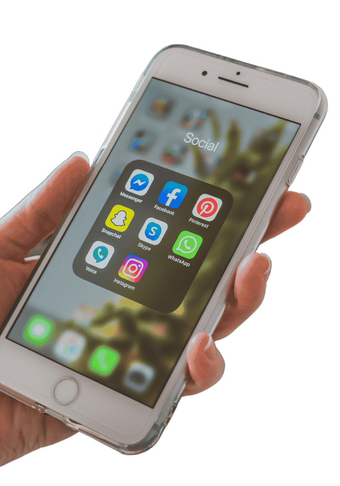 A person's hand holding a white smartphone with a clear case. The smartphone screen displays a grid of social media app icons: Messenger, Facebook, Pinterest, Snapchat, Skype, WhatsApp, Voice, and Instagram.