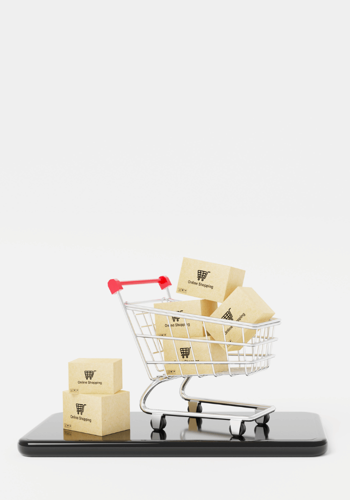 A shopping cart filled with cardboard boxes labeled "Online Shopping" sitting on top of a tablet.